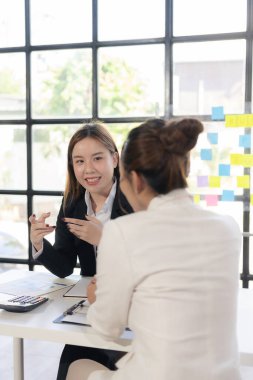 İki kadın konuşur, tartışır, yeni proje fikirleri üzerinde çalışır. Başarı sağlamak için pazarlama planlarını ve iş yatırımlarını analiz edin.