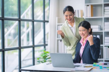 İki Asyalı iş kadını grafikler ve grafiklerle bilgisayar ekranında veri analizi çalışmaları hakkında derin bir tartışma içindeler. Takım çalışmasını göster