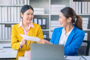 İki Asyalı iş kadını grafikler ve grafiklerle bilgisayar ekranında veri analizi çalışmaları hakkında derin bir tartışma içindeler. Takım çalışmasını göster