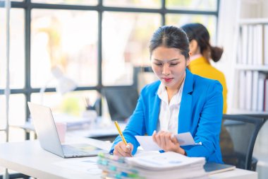 İki Asyalı iş kadını grafikler ve grafiklerle bilgisayar ekranında veri analizi çalışmaları hakkında derin bir tartışma içindeler. Takım çalışmasını göster