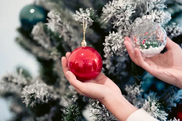 Kırmızı ve beyaz bir Noel şapkası takan genç Asyalı bir kadın hediye kutularıyla çevrili ve elinde kırmızı ya da Noel hediyesi tutuyor. Havalı, pozitif ve mutlu yeni yıl arifesi duyguları.