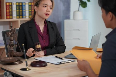 Avukat ve yetkililerden oluşan bir grup, adalet ve karar verme mekanizmasını sembolize eden çekiç ve teraziyle belgeleri kontrol ediyor.