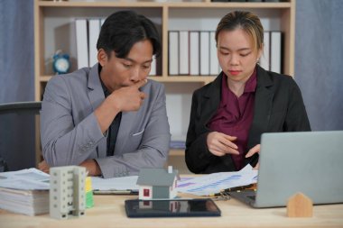 Bir emlak satış temsilcisi gayrimenkul yatırım belgelerinin yanı sıra ev satış sözleşmesi ve ev sigortasını müşterilere açıklamak için konuşur.