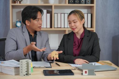 Bir emlak satış temsilcisi gayrimenkul yatırım belgelerinin yanı sıra ev satış sözleşmesi ve ev sigortasını müşterilere açıklamak için konuşur.