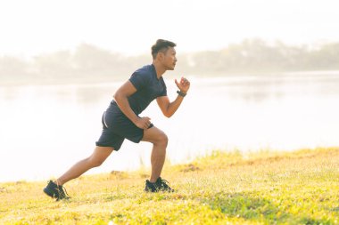 Parkta koşan bir adam güneşli bir günde koşar Gülümser ve açık hava aktiviteleriyle, motivasyonla, fitness ile, egzersizle eğlenir. Koşup gidenlere,