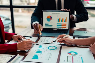 Mali raporlar, çizelgeler ve veri analizinin yer aldığı bir iş toplantısı veya tartışma. Katılımcılar, büyük olasılıkla performans ölçümleri veya stratejileri tartışan görsel bir sunumu gözden geçiriyorlar.