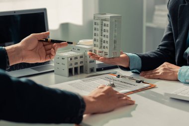 Bir emlakçı ev satın alma sözleşmesinin şartlarını açıklıyor. Müşteri yasal olarak sözleşmeyi imzalıyor.