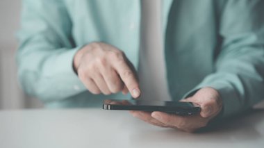 Sosyal medya telefonu ve dinlenme odası tutan bir adam. Akıllı telefondan yazıp internetten iletişim kurmak. Bildirimleri, mobil bağlantıları ve teknolojiyi okuyorum. Yakın plan fotoğraf..