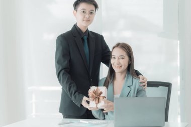 Genç Asyalı iş adamı, yıldönümlerinde ya da yeni yılda masada çalışan kız arkadaşına hediye verir..