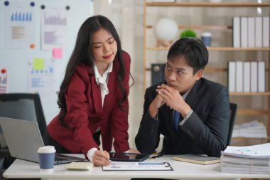 İş ortakları yeni bir proje üzerinde birlikte çalışıyorlar. Toplantıda hesap makinesi kullanarak finansal belgeleri analiz ediyorlar. Çalışma masasında konuşurken, iş problemlerini çözmek için grafik ve grafiklerdeki verileri analiz edin.