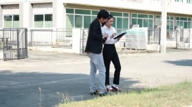 İki Asyalı yatırımcı, bir kadın ve bir erkek, bir köy inşaat projesine gitmek için yürüyorlar. Ev detayları, yeni ev satın alma fikirleri