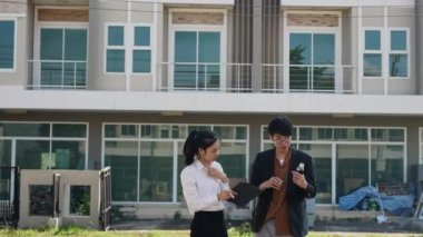 İki Asyalı yatırımcı, bir kadın ve bir erkek, bir köy inşaat projesine gitmek için yürüyorlar. Ev detayları, yeni ev satın alma fikirleri