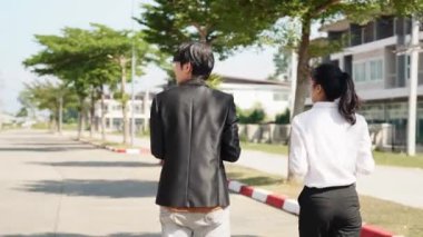 İki Asyalı yatırımcı, bir kadın ve bir erkek, bir köy inşaat projesine gitmek için yürüyorlar. Ev detayları, yeni ev satın alma fikirleri