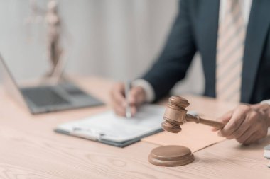 Hukuk bürosundaki erkek avukat ikonla çalışıyor ve adalet ve hukuki konsepti ayarlıyor. Tahta masa ve avukat ya da avukatla mahkeme salonunda erkek hakim.