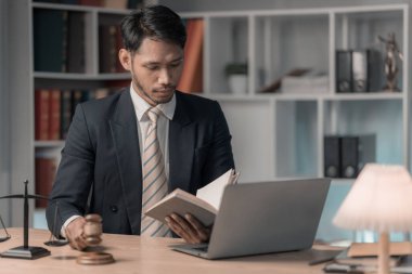 Hukuk bürosundaki erkek avukat ikonla çalışıyor ve adalet ve hukuki konsepti ayarlıyor. Tahta masa ve avukat ya da avukatla mahkeme salonunda erkek hakim.