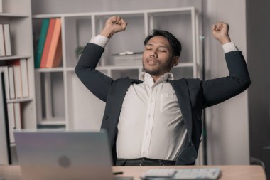 İşten yorgun ve gevşemiş genç bir adam ellerini kaldırdı. Çalışırken dinlen.