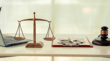 Çevrimiçi hukuk ve adalet kavramı modern ofisteki masada. Masadaki ahşap çekiç ve adalet terazisinin yanında yakın plan bir figür var.