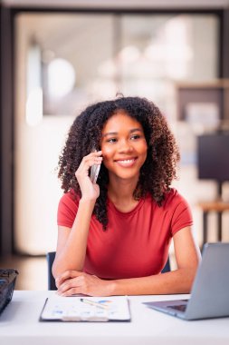 Cep telefonuyla konuşan genç Afrikalı kadın ofisteki müşteri destek ürünleri hakkında danışmanlık yapmayı düşün..