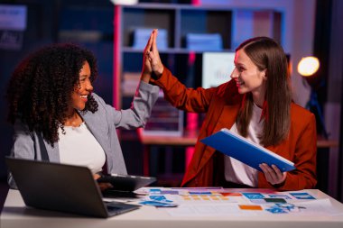 İki gülümseyen profesyonel iş kadını başarılı kadın çift iş hedeflerine ulaşmayı kutluyor, iş başarısını iş yerinde beşlik çakarak kutluyorlar.