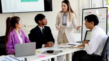 Bir grup genç iş adamı ofiste bir masada oturup kağıt raporlarını ve grafik belgelerini tartışıyor. Fikirleri paylaşın, kararlar verin ve iş sorunlarına beyin fırtınası çözümleri getirin..