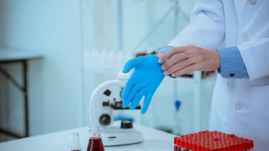 Bilim adamları steril tek kullanımlık eldiven laboratuvarında deneyler yapmadan önce mavi lastik eldiven giyerler. Tıbbi ve cerrahi eldivenler, sağlık hizmetleri ve tıbbi konsept