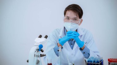Bilim laboratuarında kimyasal test yapan erkek bilim adamı, laboratuarda mavi cam tüp, cam tüpte sıvı tutan Asyalı erkek doktor, tıbbi kimya alanında çalışıyor..