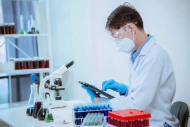 Bilim laboratuarında kimyasal test yapan erkek bilim adamı, laboratuarda mavi cam tüp, cam tüpte sıvı tutan Asyalı erkek doktor, tıbbi kimya alanında çalışıyor..