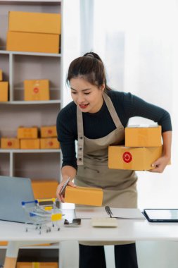 Çevrimiçi KOBİ İş Fikirleri Küçük İş KOBİ işletme sahibi Asyalı bayan girişimci müşterilere satacak kutular hazırlamak için kutu kutu ve çevrimiçi siparişleri kontrol ediyor. Dikey resim.