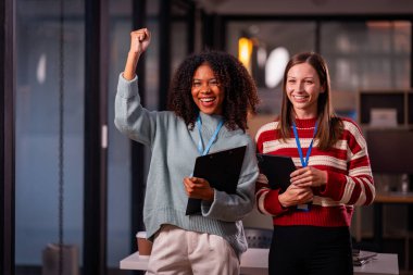 Kafkas işadamı ve genç Afrikalı kadın modern ofiste proje başarısını kutluyor. Tasarım prototipini tutun ve heyecanınızı gösterin..