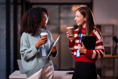 Beyaz iş adamı ve Afrikalı kadın takım olarak çalışır ve gece araştırmaları için laptop tableti kullanırlar. Veri analizi sonuçları dijital teknolojiyle karşılaştırma ve planlama