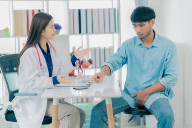 Genç adam idrar yolu enfeksiyonu ve cinsel fonksiyon kaybı konusunda doktora danışmanlık yapıyor. İdrar yolundaki ağrı. Genç adam, prostat bölgesindeki sağlık kavramını sıkıyor.