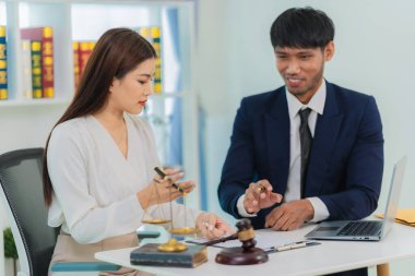 Erkek avukat sözleşme belgelerini tartışıyor, iş kadını danışma masasında oturuyor, hukuki danışmanlık hizmeti ve yanında yargıç çekici olan bir tartı..