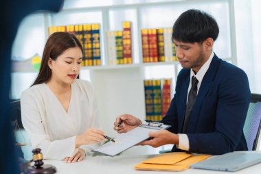 Erkek avukat sözleşme belgelerini tartışıyor, iş kadını danışma masasında oturuyor, hukuki danışmanlık hizmeti ve yanında yargıç çekici olan bir tartı..