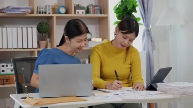 Mutlu Asyalı son sınıf öğrencisi kız ve anne dizüstü bilgisayar kullanarak online bankacılık, borç alma, ev finansmanı.