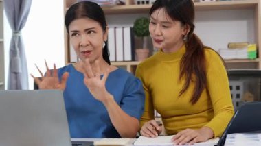 Mutlu Asyalı son sınıf öğrencisi kız ve anne dizüstü bilgisayar kullanarak online bankacılık, borç alma, ev finansmanı.