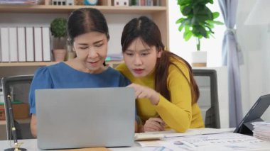 Mutlu Asyalı son sınıf öğrencisi kız ve anne dizüstü bilgisayar kullanarak online bankacılık, borç alma, ev finansmanı.