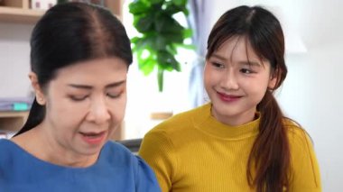 Mutlu Asyalı son sınıf öğrencisi kız ve anne dizüstü bilgisayar kullanarak online bankacılık, borç alma, ev finansmanı.