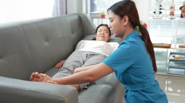 Asyalı kadın fizyoterapist, kas dokusu zedelenmesi olan yaşlı bir kadın hastayla ilgileniyor..