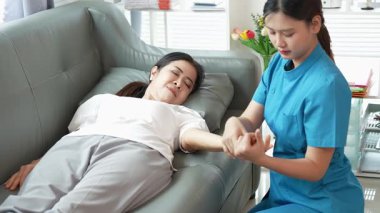 Asyalı kadın fizyoterapist, kas dokusu zedelenmesi olan yaşlı bir kadın hastayla ilgileniyor..