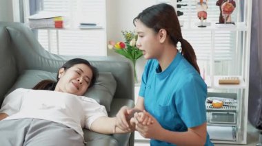 Asyalı kadın fizyoterapist, kas dokusu zedelenmesi olan yaşlı bir kadın hastayla ilgileniyor..