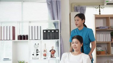 Asyalı kadın fizyoterapist, kas dokusu zedelenmesi olan yaşlı bir kadın hastayla ilgileniyor..