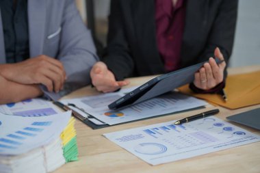 Ofis çalışanları dizüstü bilgisayarlar ve dijital tabletlerle birlikte çalışarak çeşitli belgelerdeki verileri analiz ediyorlar. Toplantıyı özetlemeden ve sunmadan önce