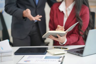 Ofis çalışanları dizüstü bilgisayarlar ve dijital tabletlerle birlikte çalışarak çeşitli belgelerdeki verileri analiz ediyorlar. Toplantıyı özetlemeden ve sunmadan önce