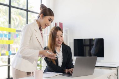 İki Asyalı kadın yeni proje fikrinin sunumuyla konuşuyor, tartışıyor, iş pazarlama planını analiz ediyor..