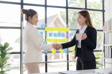 İş kadınları, ofiste yapılan başarılı bir iş anlaşması toplantısında anlaşmaya vardıktan sonra el sıkışıyorlar. Başarı ve ortaklığı kutlayın