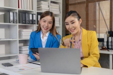 İki Asyalı kadın yeni proje fikrinin sunumuyla konuşuyor, tartışıyor, iş pazarlama planını analiz ediyor..