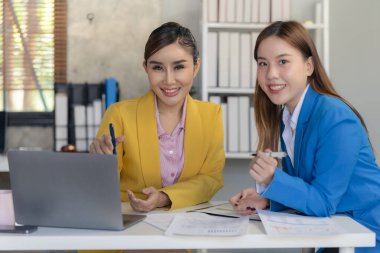 İki Asyalı kadın yeni proje fikrinin sunumuyla konuşuyor, tartışıyor, iş pazarlama planını analiz ediyor..