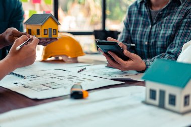 Endüstriyel mühendislerden oluşan bir ekip, makine planlarını analiz etmek için toplanıyor. Projeyi masada tartışın, ofisteki bina tasarımı projesini çizmek için dizüstü bilgisayarı kullanın. inşaat kavramı