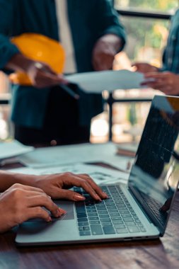 Endüstriyel mühendislerden oluşan bir ekip, makine planlarını analiz etmek için toplanıyor. Projeyi masada tartışın, ofisteki bina tasarımı projesini çizmek için dizüstü bilgisayarı kullanın. inşaat kavramı