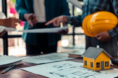 Endüstriyel mühendislerden oluşan bir ekip, makine planlarını analiz etmek için toplanıyor. Projeyi masada tartışın, ofisteki bina tasarımı projesini çizmek için dizüstü bilgisayarı kullanın. inşaat kavramı